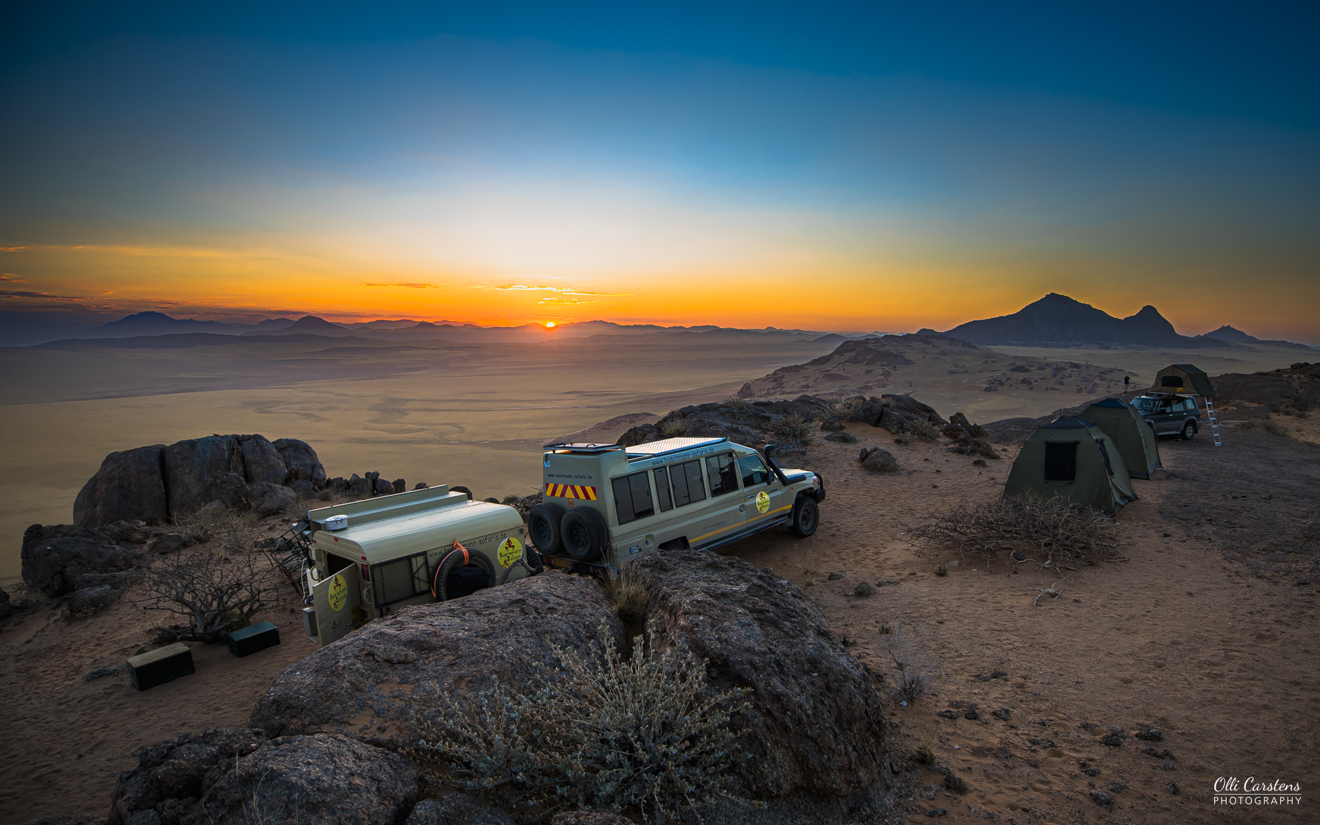 Einsamkeit und Weite im Nordwesten Namibia Geländewagen stehen in einer wüstenartigen Landschaft während des Sonnenuntergangs.