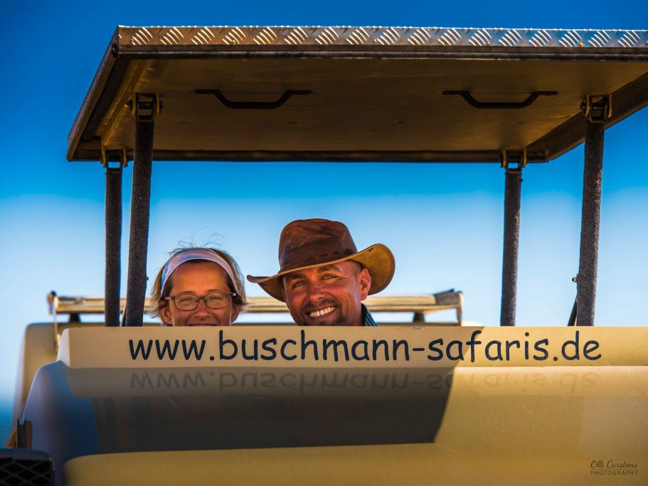 Ein Mann und eine Frau in einem Geländewagen mit einem blauen Himmel im Hintergrund.
